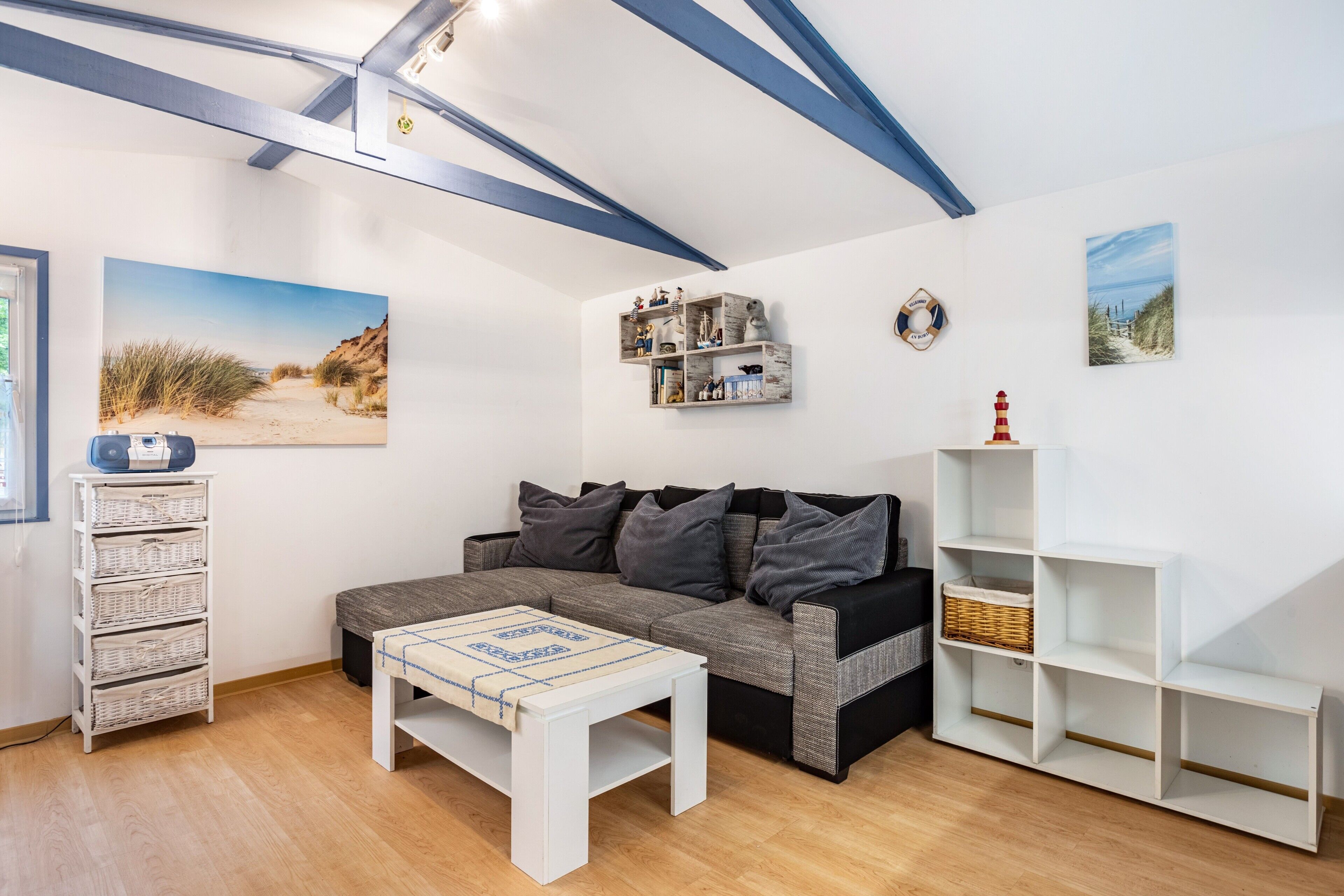 A living room with a sofa, a coffee table, a bookshelf, and wall art.