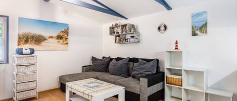 A living room with a sofa, a coffee table, a bookshelf, and wall art.