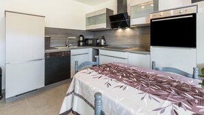 Een kleine keuken met moderne apparaten, een eethoek met een tafel en een inbouwoven.