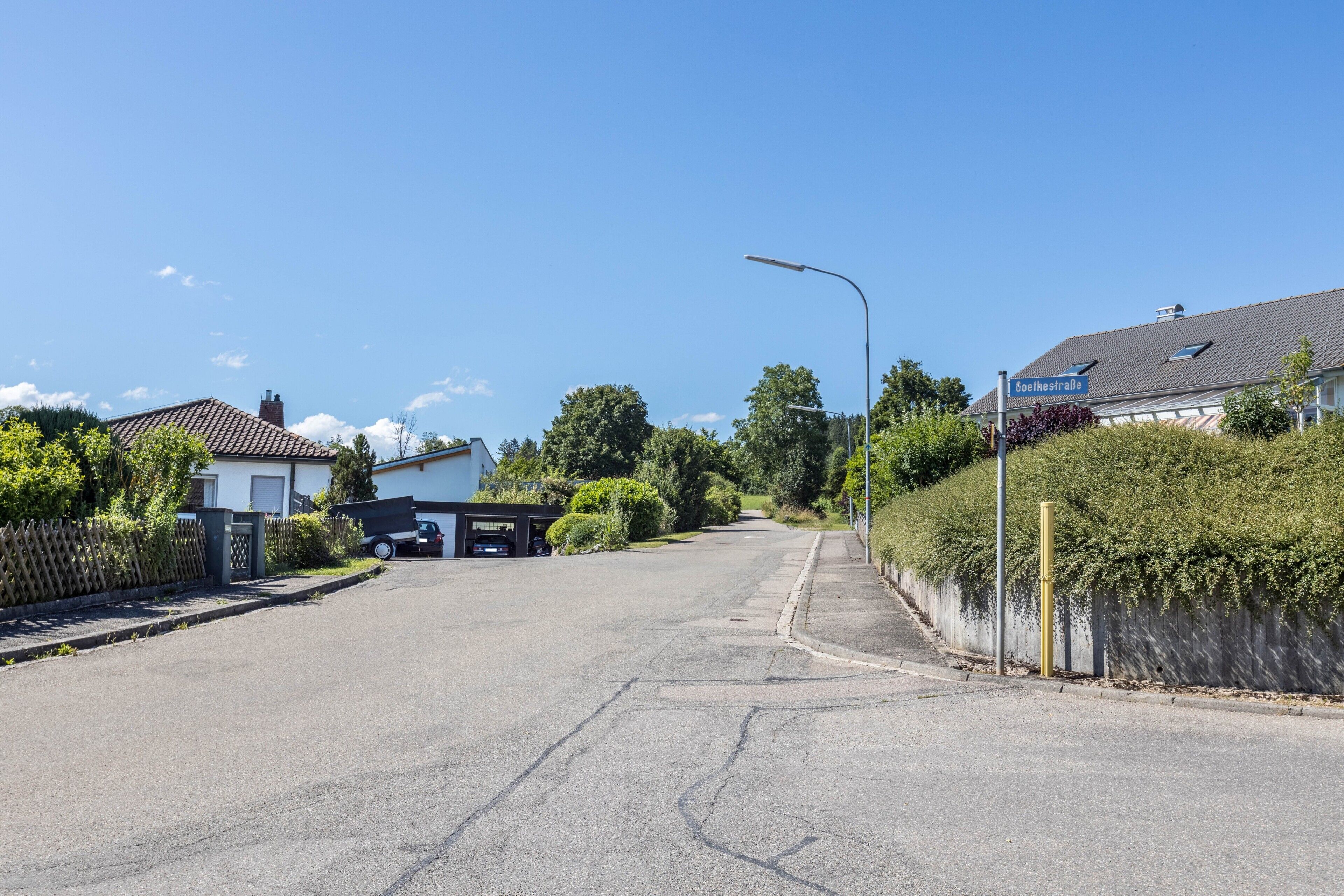 Asuinkatu, jossa on taloja, kirkas taivas ja katukyltti, jossa lukee ”Schellstraße”.