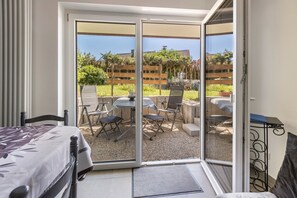 Una habitación con una cama, una mesa con sillas y un ventanal corredizo que da a un patio exterior con una mesa y sillas.