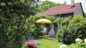 A house with a red roof, a patio with a yellow umbrella, and a garden with white flowers. - Holiday Home 'Villa Ilsebill' with Private Terrace and Garden (Ribnitz-Damgarten)