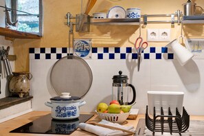 Een keuken met een fornuis, een koffiezetapparaat, een fruitschaal en een servies.