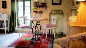 A cozy room with a round table, two chairs, a wicker sofa, a patterned rug, and a window with curtains. - Holiday Home 'Villa Ilsebill' with Private Terrace and Garden (Ribnitz-Damgarten)
