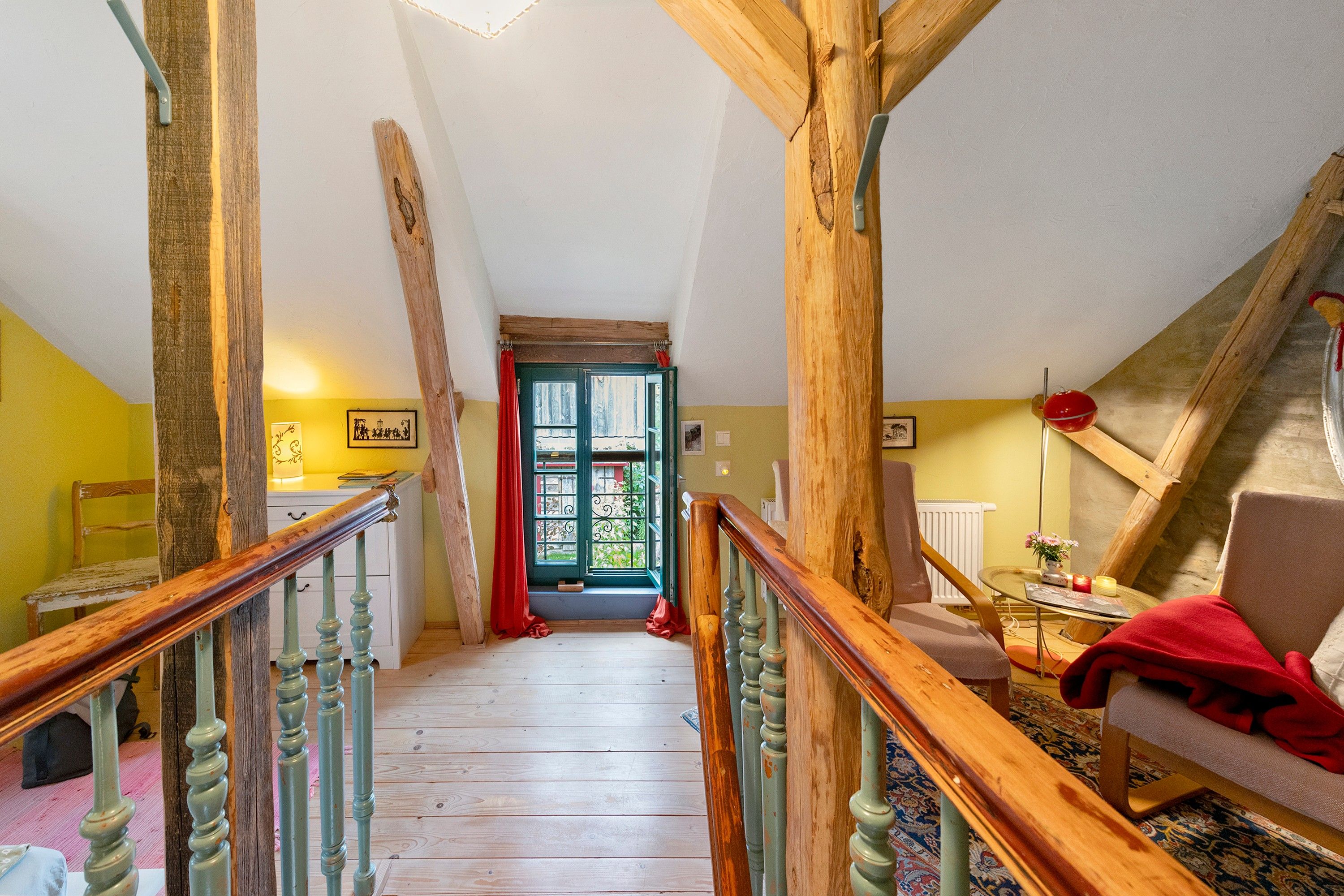 A wooden staircase leading to a door with a view of greenery outside.