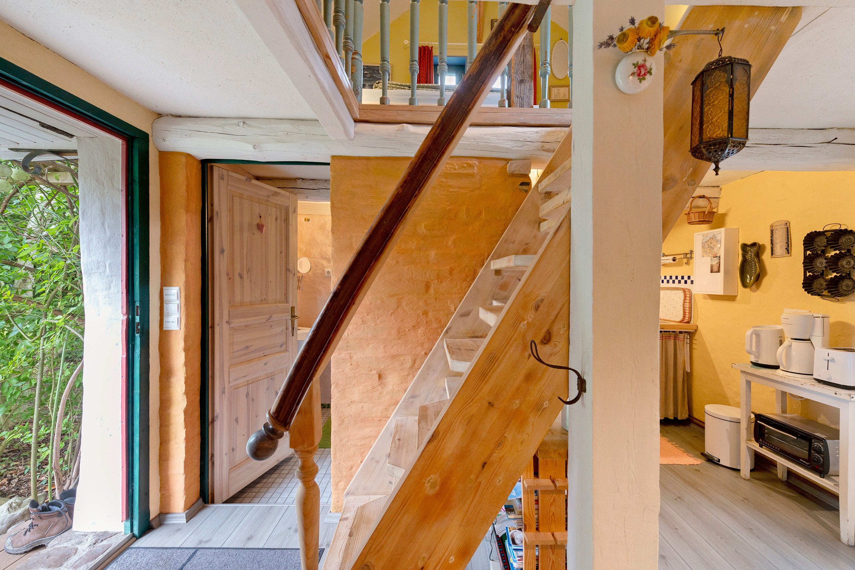 A wooden staircase leading to a second-floor area with a kitchen and a dining area.