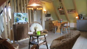Ein gemütliches Wohnzimmer mit Fernseher, ein Essbereich mit Tisch und Stühlen sowie eine Küchenzeile mit einem Schrank.