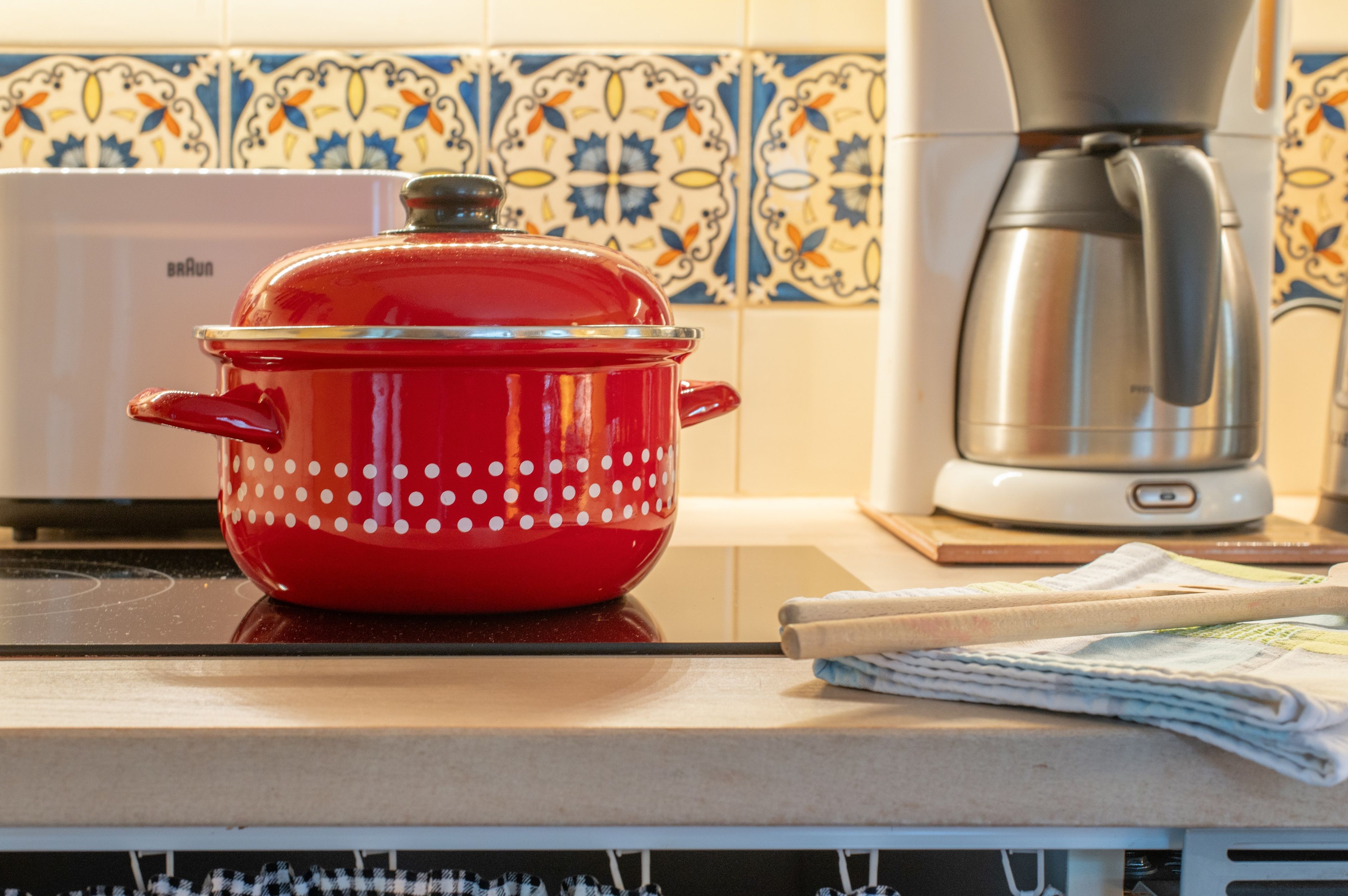 Una olla de cocción lenta roja con lunares blancos sobre una encimera de cocina.