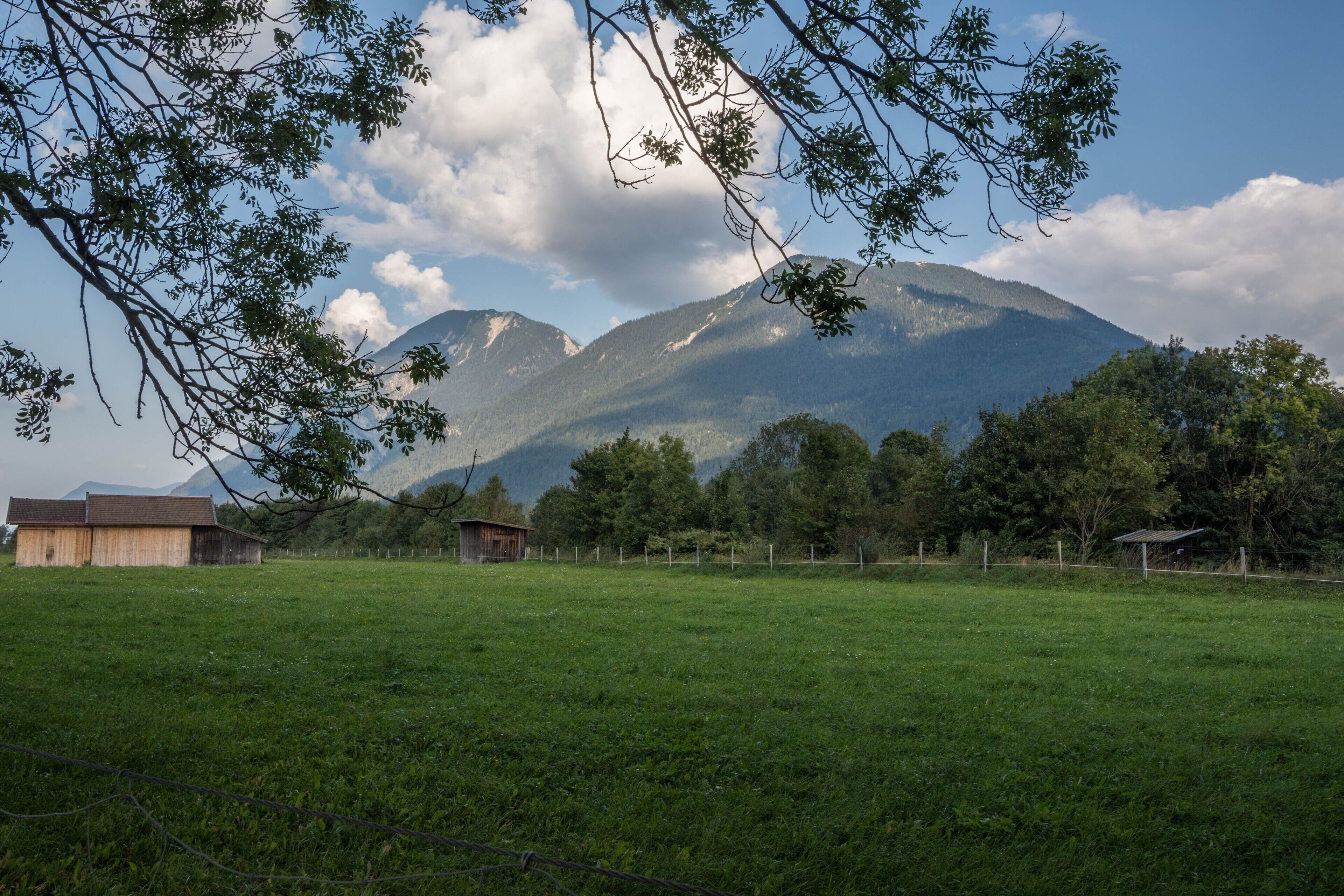 A rural landscape with a mountain, a barn, and a fenced field.