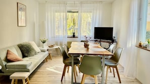 Un espace repas comprenant une table en bois, des chaises, un canapé et un téléviseur.