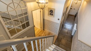Un escalier avec une rampe, un luminaire fixé au mur et une porte en bas.