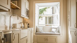 Une cuisine dotée d’une banquette intégrée près de la fenêtre, de meubles blancs et d’un dosseret en carreaux disposés en motif chevron.