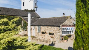 A stone building with a bell tower, stone walls, and hanging flower baskets. - Sun Hill Palins -  a cottage that sleeps 2 guests  in 1 bedroom (Leyburn)