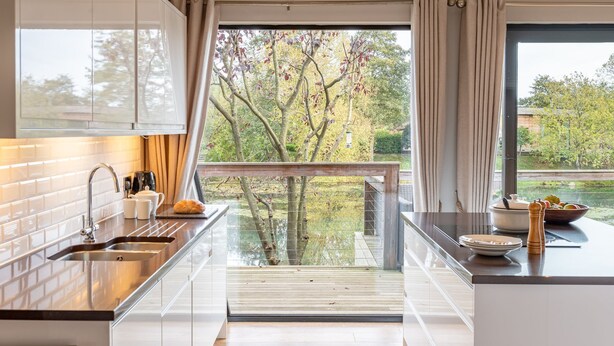 A modern kitchen with a large window, a wooden deck, and a view of trees. - Abbey -  a lodge that sleeps 6 guests  in 3 bedrooms (Richmond)