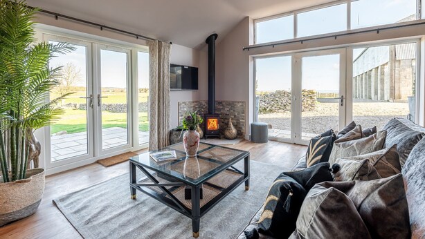 A spacious living room with a glass coffee table, a sofa, and a fireplace. - Bearskin Cottage - Holiday At Home (Leyburn)