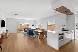 A modern kitchen with a central island, built-in appliances, and a large window providing natural light.