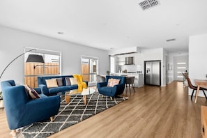 Un salon moderne avec un canapé bleu, une table basse et un coin repas comprenant une table et des chaises en bois.