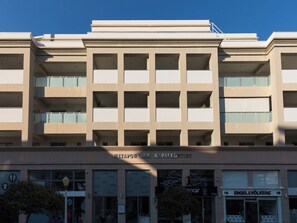Edifício de vários andares com design arquitetônico moderno, com uma série de varandas e grandes janelas.