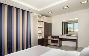 Quarto de hotel com cama, escrivaninha, armário e janela com vista para a cidade.
