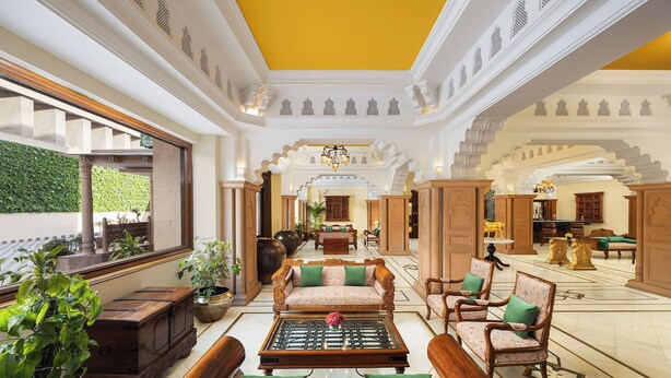 Un hall espacioso con muebles ornamentales, una mesa de centro y vistas al jardín a través de amplios ventanales.