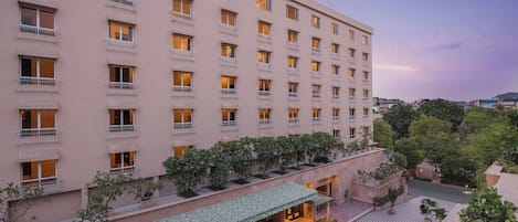 A multi-story hotel with balconies, outdoor seating, and a courtyard with potted plants.