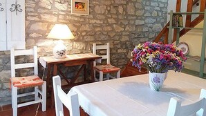 A dining area with a stone wall, a table with chairs, a lamp, and a vase of flowers. - Casa Brina B: A characteristic and welcoming two-story independent house made of stone, with Free WI-FI. (Monte Santa Maria Tiberina)