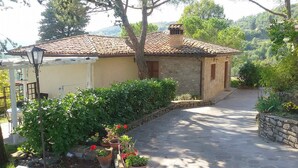 Une maison de campagne en pierre, avec un toit en tuiles, un chemin pavé et une végétation luxuriante.
