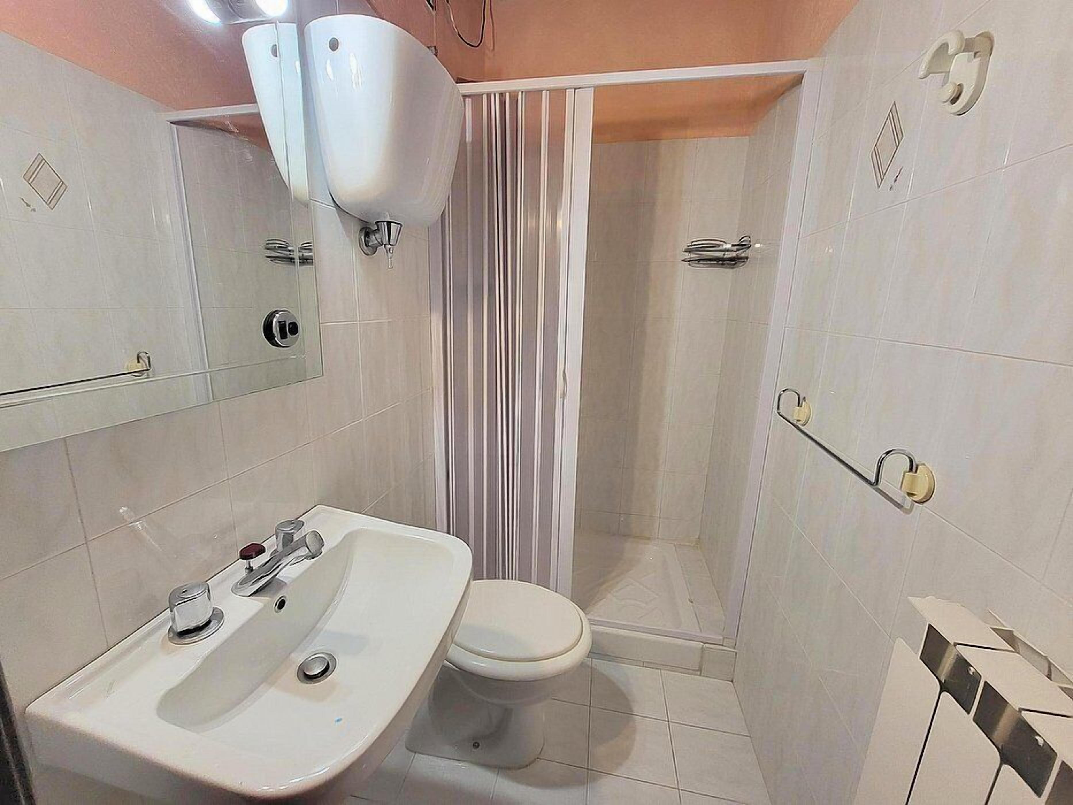 A bathroom with a sink, toilet, and shower area.