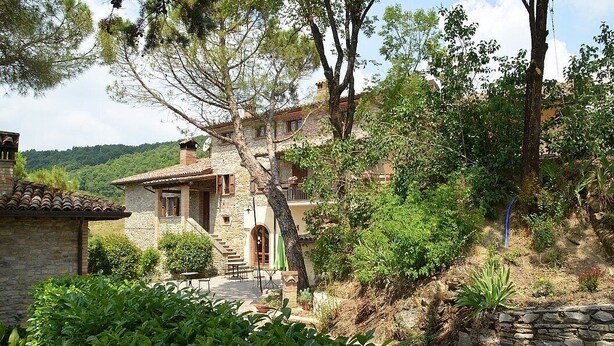 A stone house with a tiled roof, surrounded by lush greenery and a stone wall. - Casa Brina E: A characteristic and welcoming apartment that is part of an ancient country house made of stone, with Free WI-FI. (Monte Santa Maria Tiberina)