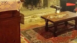 Una sala de estar acogedora con chimenea, un banco de madera y un tapete estampado.