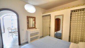 Un dormitorio con cama, cómoda, espejo y puerta que da a un balcón.