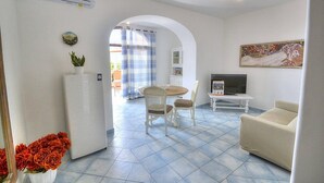 Una sala de estar con comedor, un sofá, un televisor y un refrigerador.