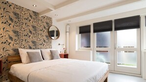 A bedroom with a large bed, a round mirror, and a window with blinds. - Pakhuis aan de Zaan Wormerveer (Wormerveer)