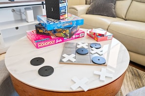 Une table basse ronde, sur laquelle on trouve divers jeux de société et accessoires de jeu.