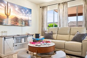 Ein Wohnzimmer mit einer Couch, einem Couchtisch und einem Wand-Fernseher.