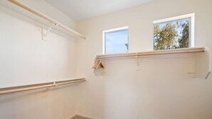 Ein Zimmer mit Fenster, einem Holzbalken und einem an der Wand befestigten Regal.