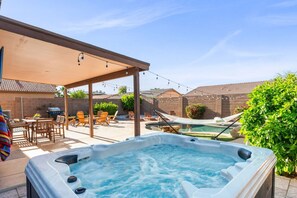 Ein Garten mit Whirlpool, Terrassenmöbeln und Schwimmbecken.