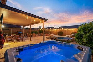 Ein Garten mit Whirlpool, Gartenmöbeln und Lichterketten.
