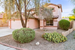A residential house with a garage, a tree, and a cactus garden.