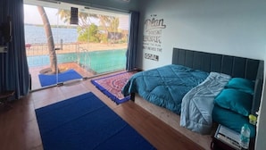 A bedroom with a bed, a blue mat, a motivational quote on the wall, and a view of a pool and palm trees. - Blue Lagoon Homestay (Mangaluru)
