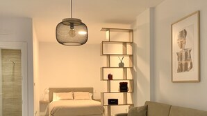 A modern living room with a beige sofa, a white coffee table, and a hanging light fixture. - Cozy Studio in Distrito Centro Malaga (Málaga)