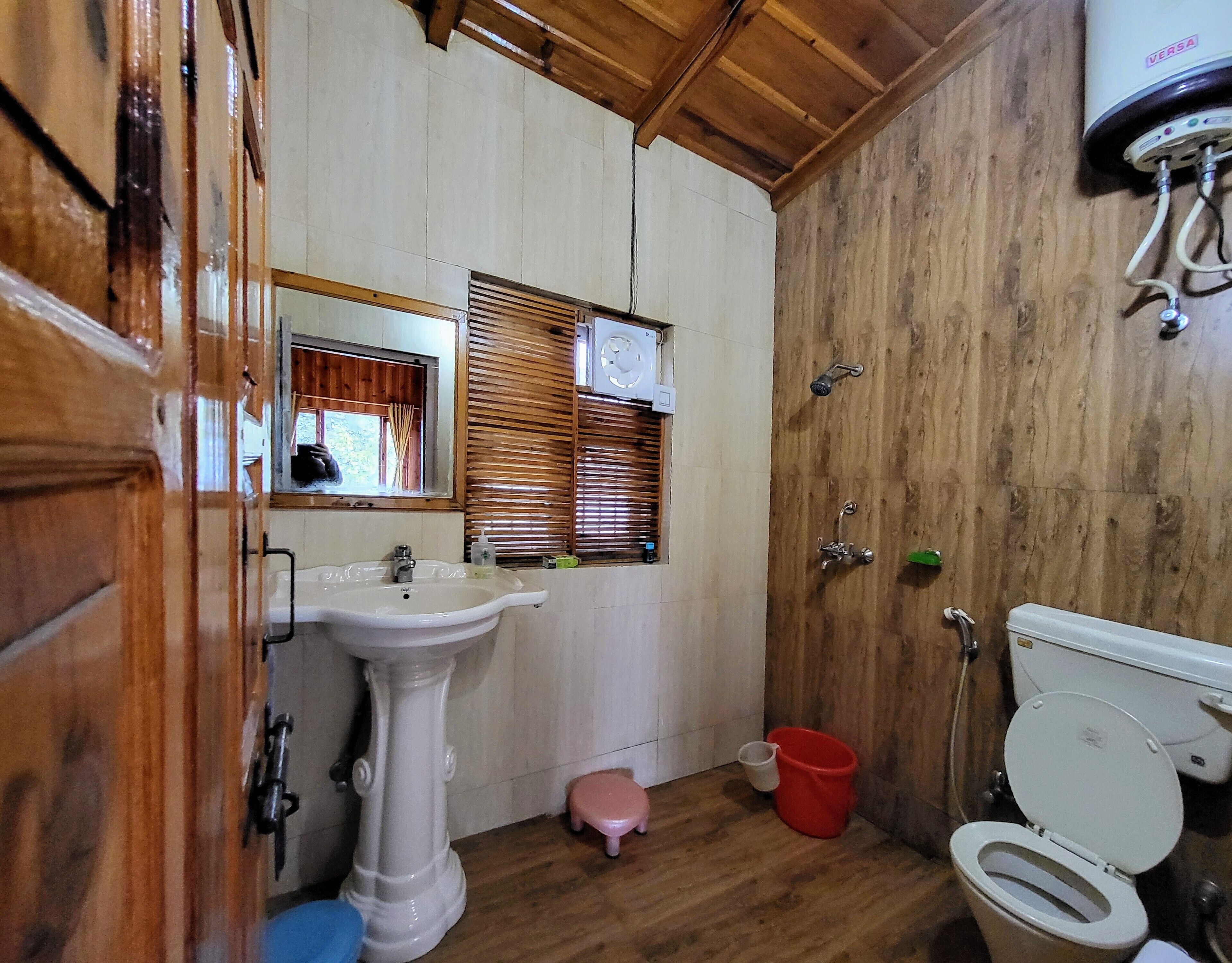 Une petite salle de bain comprenant un lavabo sur colonne, des toilettes et une douche.