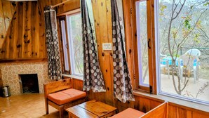 A cozy room with wooden walls, a stone fireplace, and a view of the outdoors. - Hartola Panorama Cottage (Kosiyakutoli)