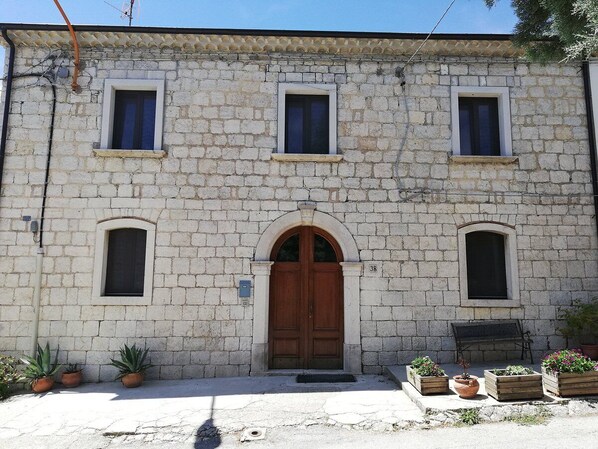 A stone building with a central arched door, three windows, and potted plants. - B&B Santo Stefano (Campobasso)