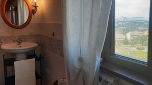 A bathroom with a sink, mirror, and window with a view of buildings. - B&B Santo Stefano (Campobasso)