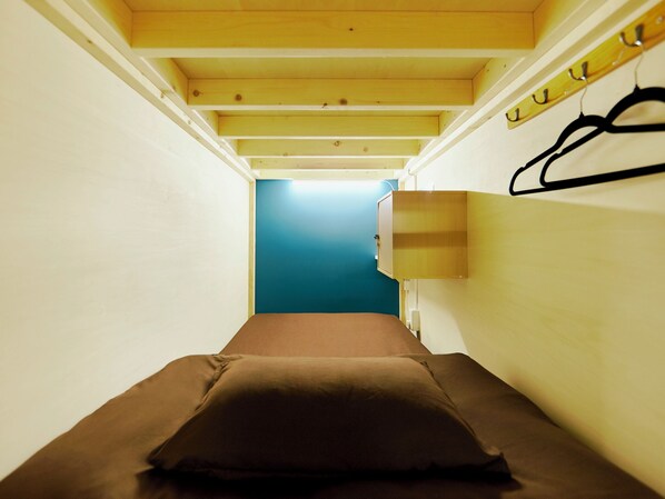 Un pasillo estrecho que conduce a una habitación con cama, pared azul y techo de madera.