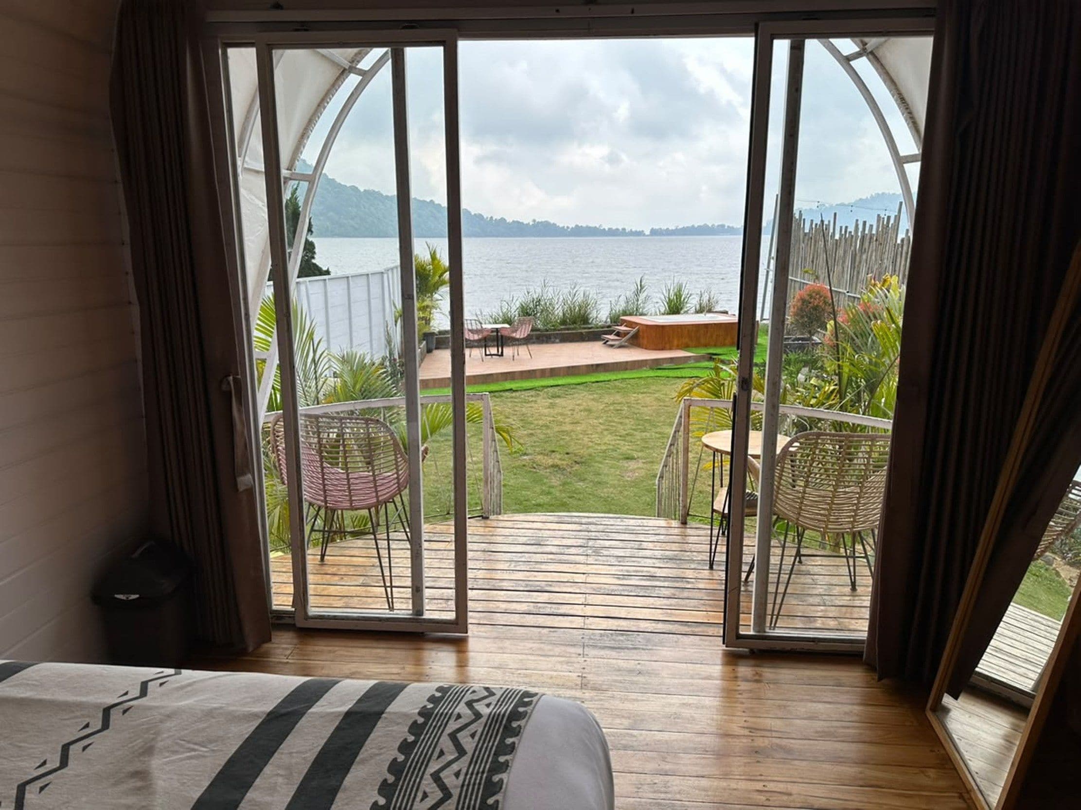 Ein Zimmer mit einer großen Schiebetür, die auf eine Terrasse mit Blick auf einen See und Berge führt.