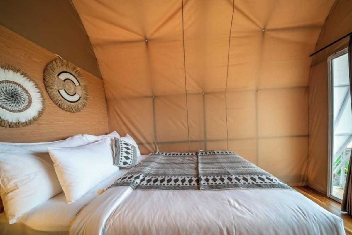 Una stanza a forma di tenda con un letto, cuscini e una coperta.