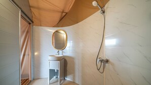 Een kleine badkamer met een wastafel, spiegel en douche.
