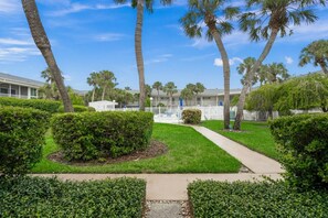 A pathway leading to a building with a white fence and palm trees. - Walk to Lido Beach & St. Armands! Heated Pool/Spa (Sarasota)